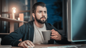 Guy drinking coffee while using his computer